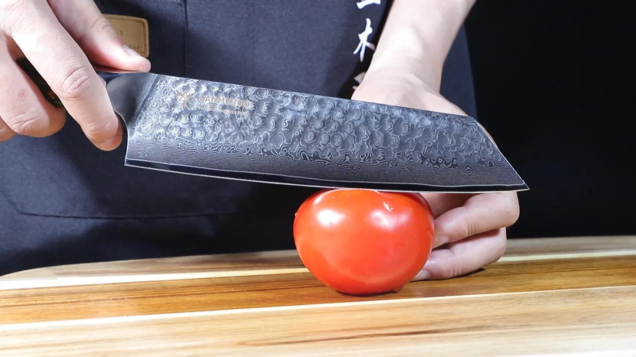 A SANMUZUO kitchen knife preparing a tomato on a wooden board